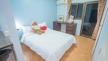 Un dormitorio con cama, escritorio y ventana con cortinas.