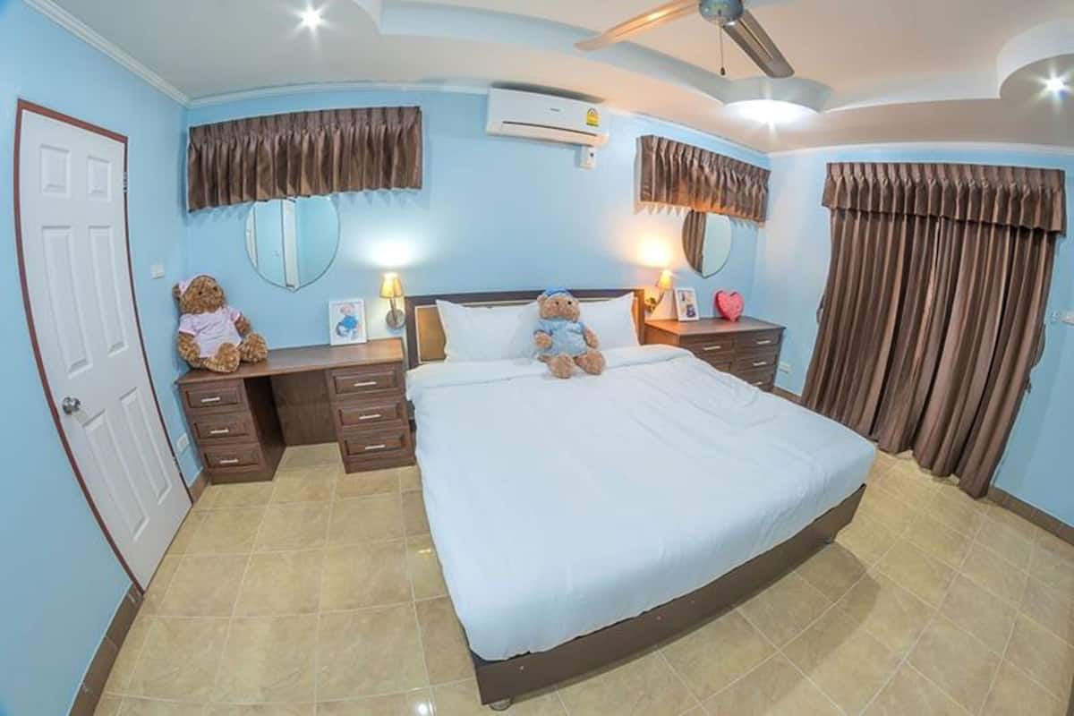 A bedroom with a bed, two bedside tables, a desk, a chair, a ceiling fan, and a window with curtains.