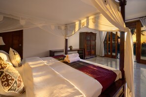 A spacious bedroom with a large bed, a wooden cabinet, and a view of the outdoors. - Balangan Beach Villa (Jimbaran)