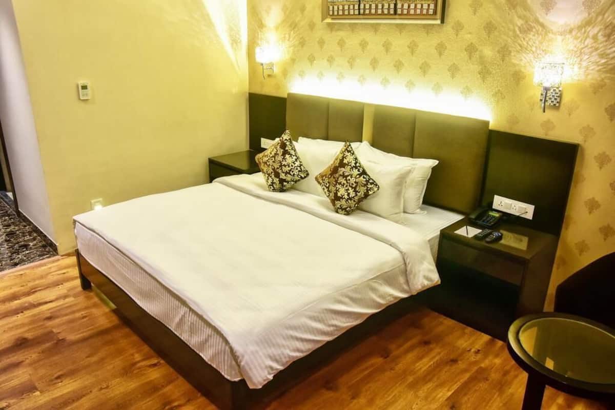 A hotel room with a bed, nightstands, a chair, and a wall-mounted light fixture.