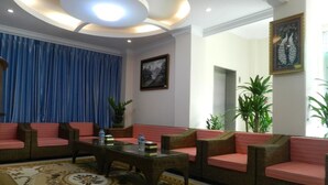 A lounge area with wicker sofas, a glass coffee table, and a patterned rug. - Real Link Hotel (Yangon)