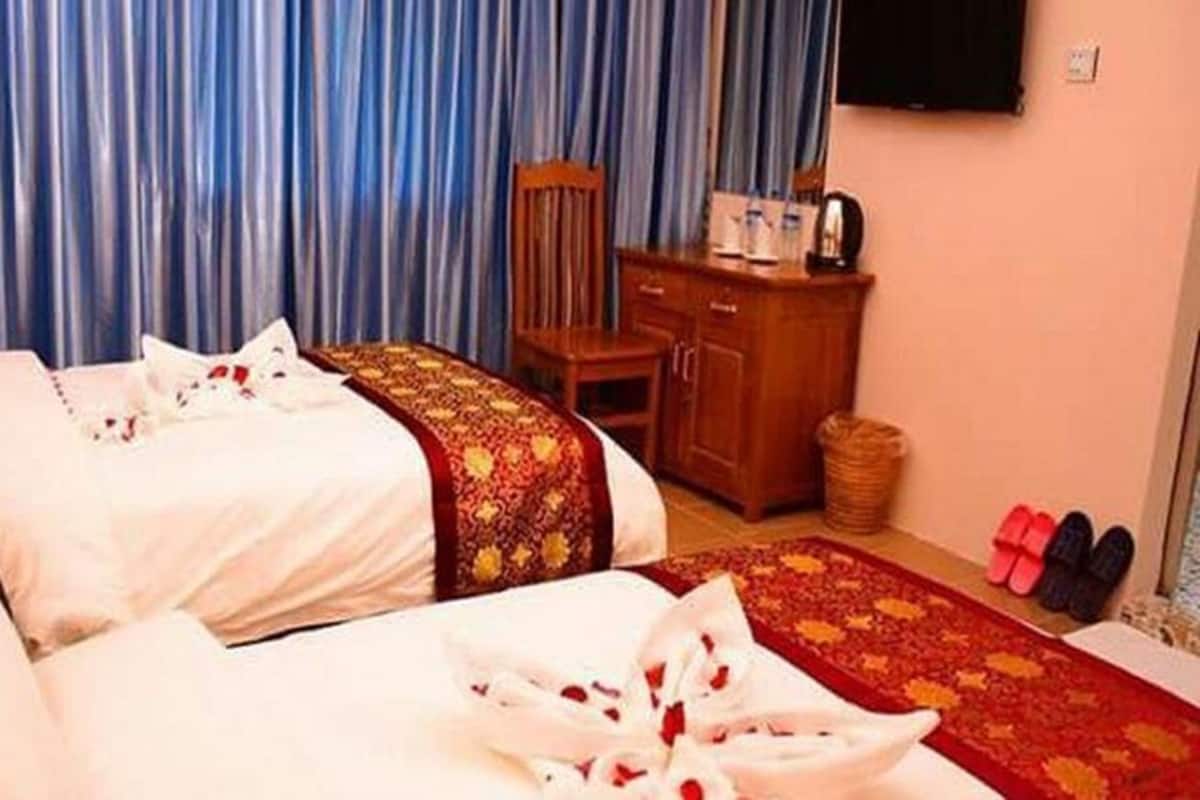Una habitación de hotel con dos camas, un armario de madera y una alfombra roja.
