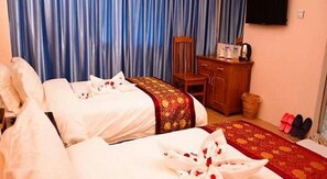 Una habitación de hotel con dos camas, un armario de madera y una alfombra roja.