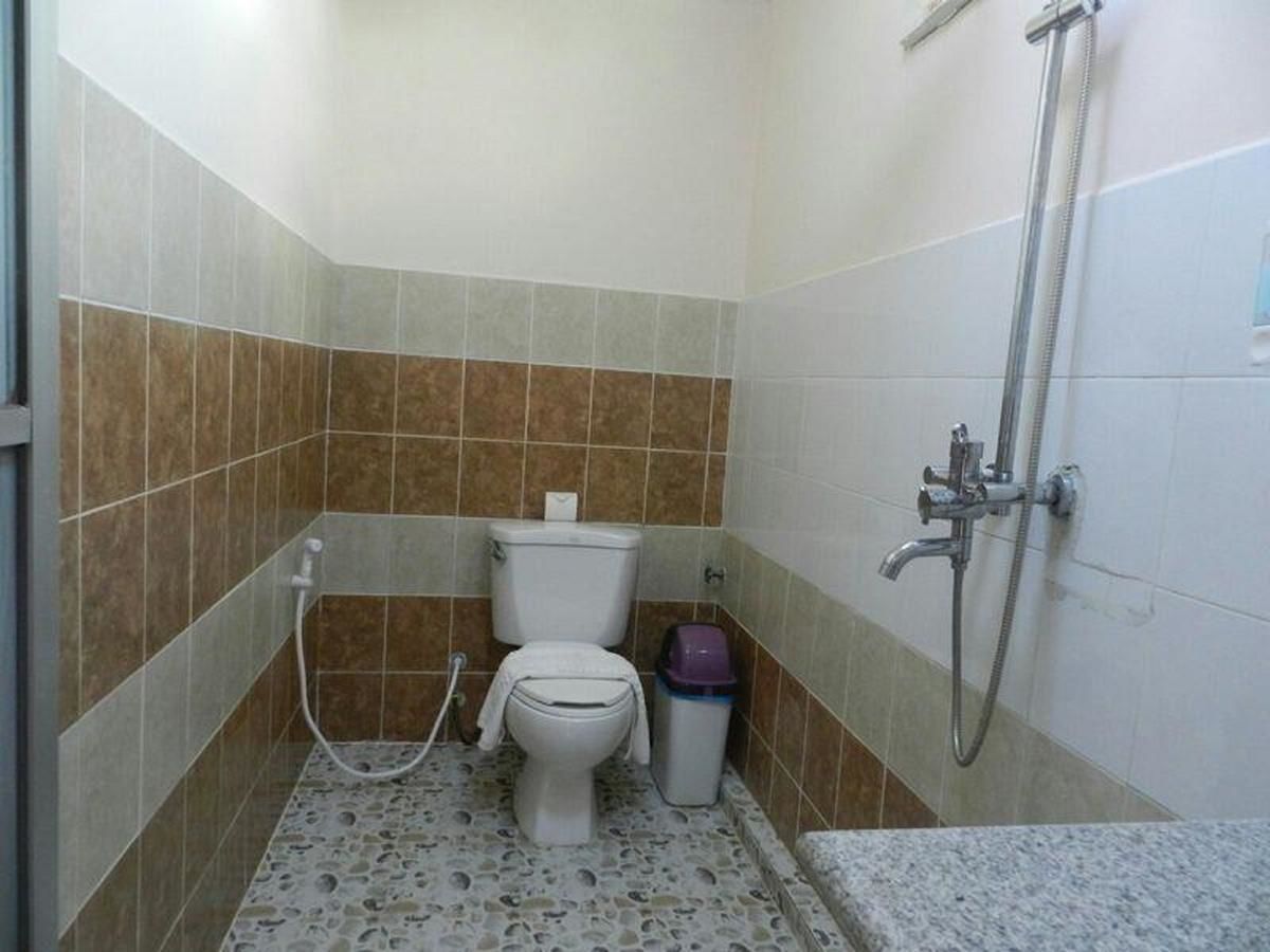 Un baño pequeño con inodoro, ducha y un cesto de basura.
