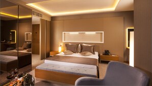 Une chambre d’hôtel moderne dotée d’un grand lit, d’un coin salon, d’un bureau et d’un miroir.