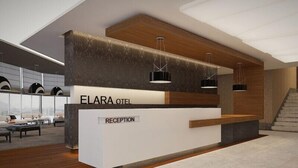 Un comptoir d’accueil portant l’inscription « ELARA OTEL », au design moderne, avec un mur d’accent en bois et des luminaires suspendus.