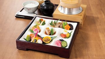 A traditional Japanese meal with various dishes and a tea set on a wooden table.