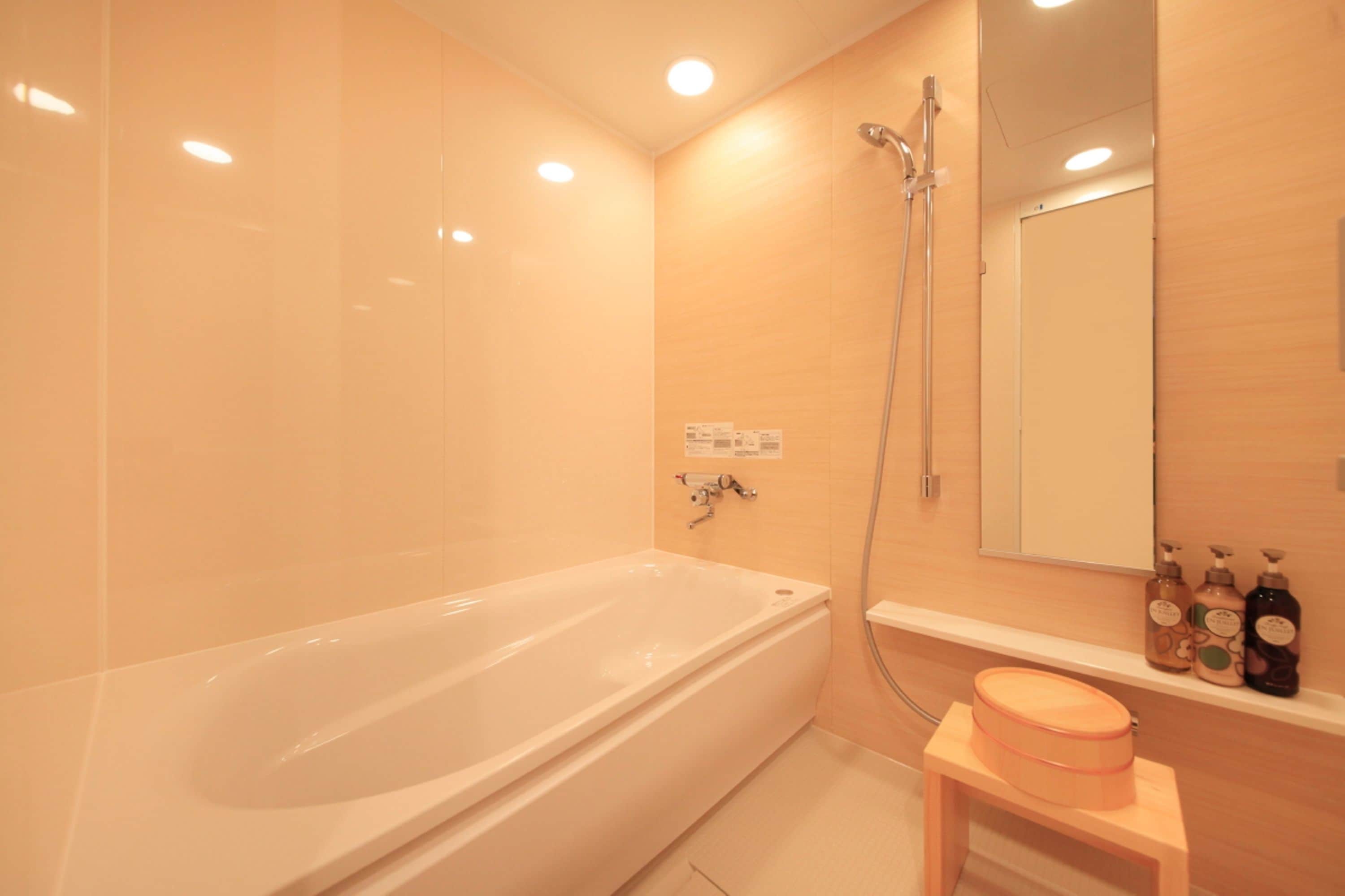 A modern bathroom with a large bathtub, a shower, and a vanity with toiletries.