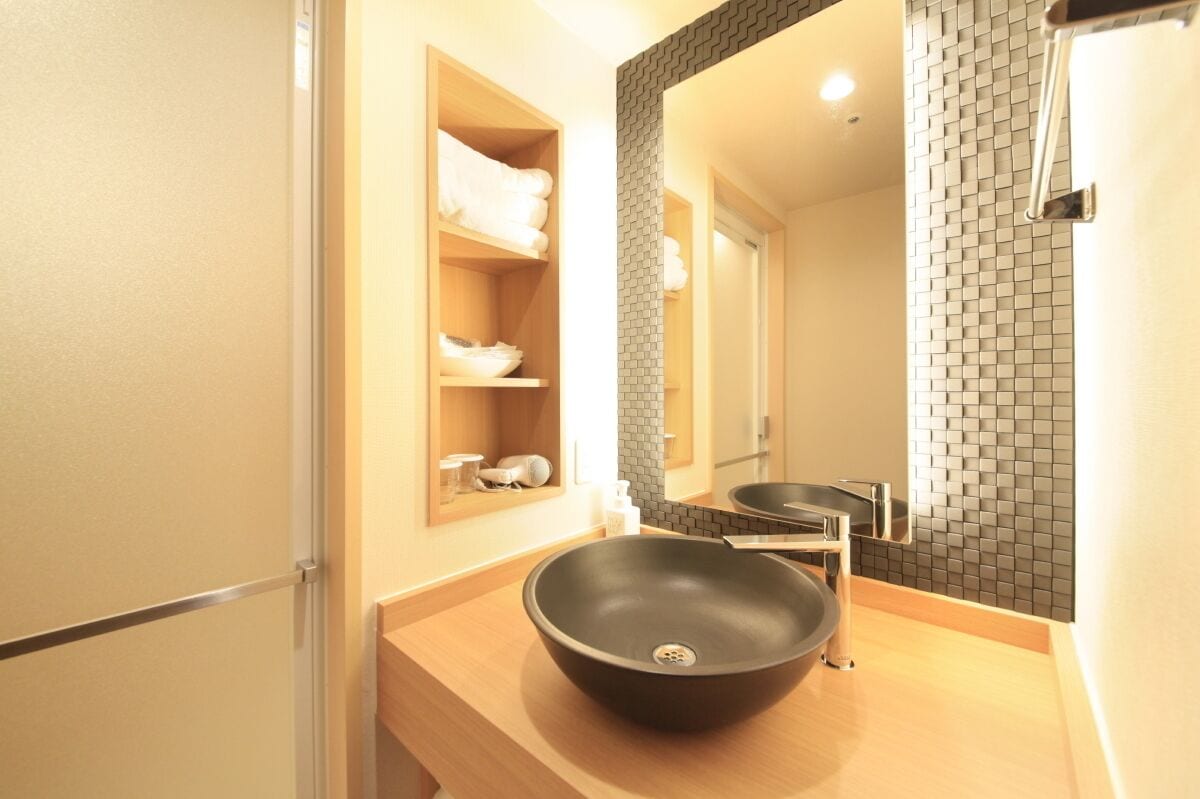 Une salle de bain moderne avec un lavabo sur pied noir, un miroir et une étagère avec des serviettes.