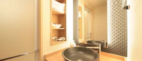 Une salle de bain moderne avec un lavabo sur pied noir, un miroir et une étagère avec des serviettes.