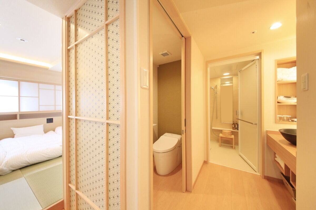 Et hotelværelse med seng, toilet, bruseområde og håndvask.