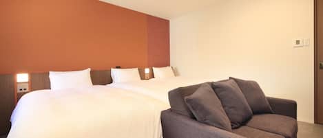 Quarto de hotel com duas camas, um sofá e cabeceira de madeira.