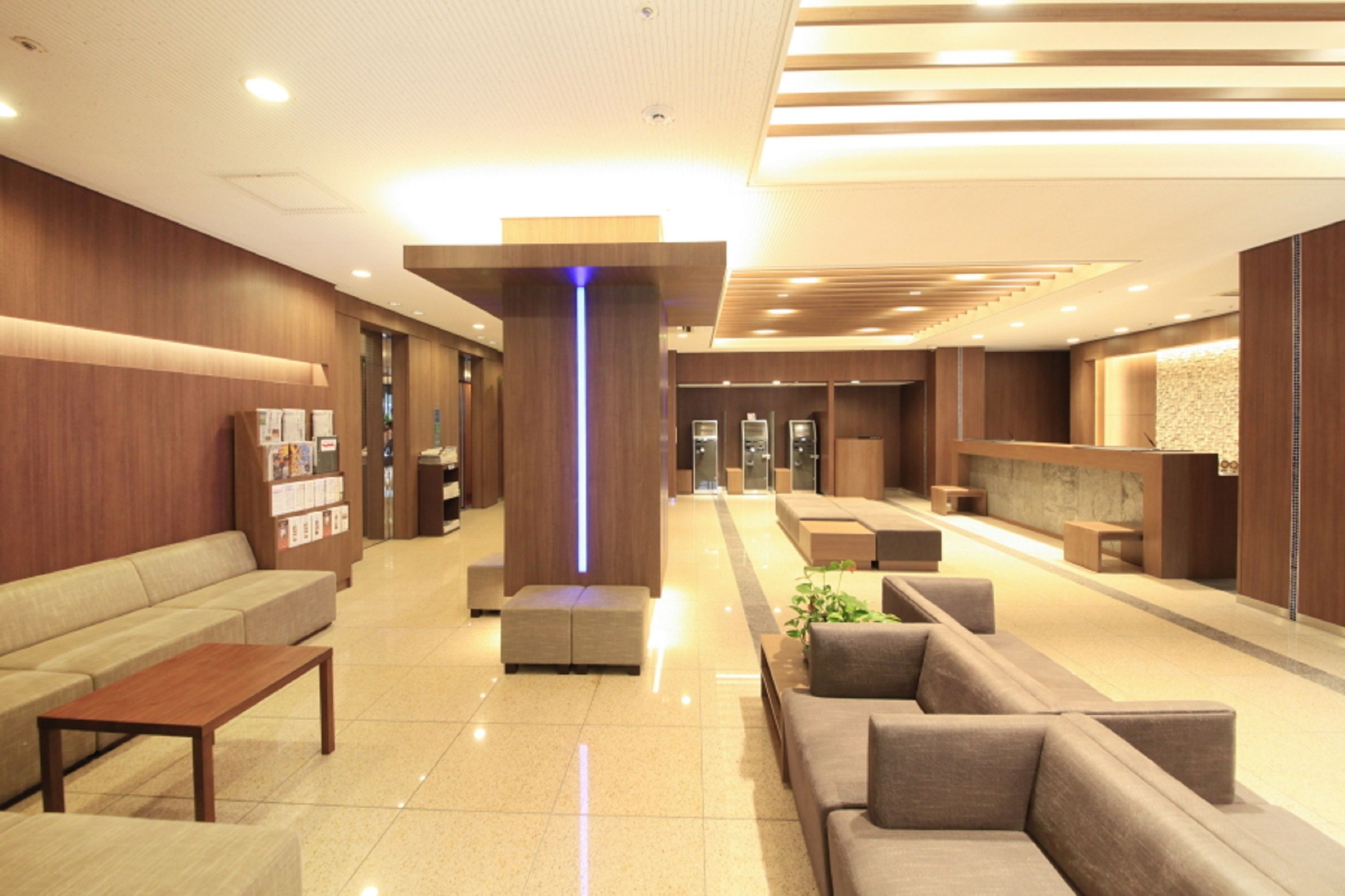Um lobby moderno com áreas de estar, um balcão de recepção e um elemento de iluminação vertical.