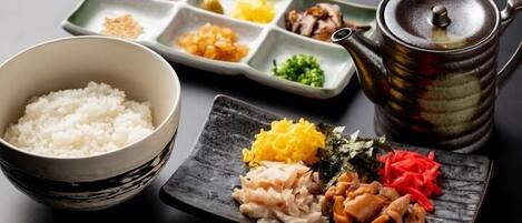 Un repas japonais traditionnel, composé d’un bol de riz, d’un plat compartimenté contenant divers ingrédients et d’une théière.