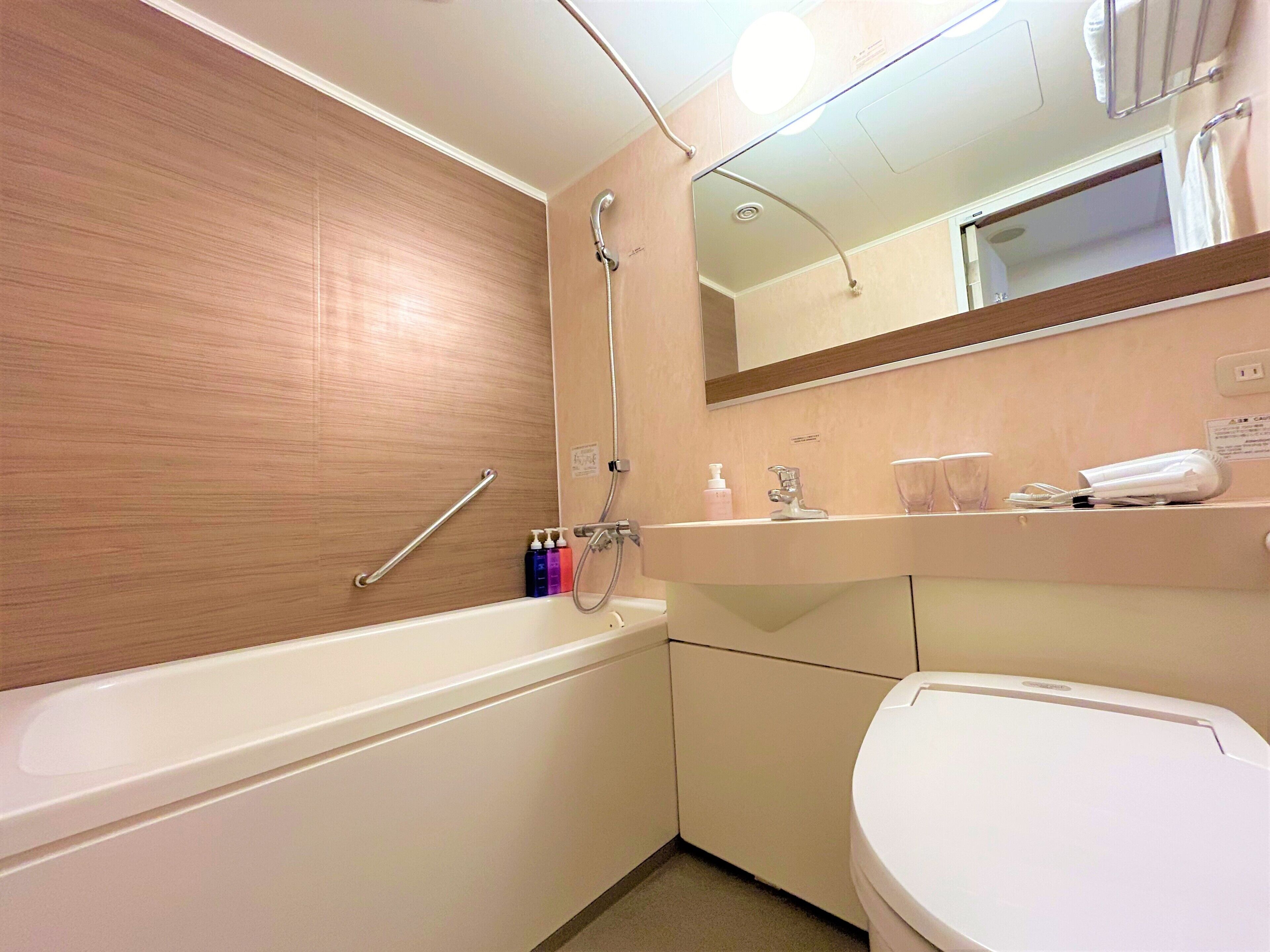A bathroom with a bathtub, a sink, a toilet, and a mirror.