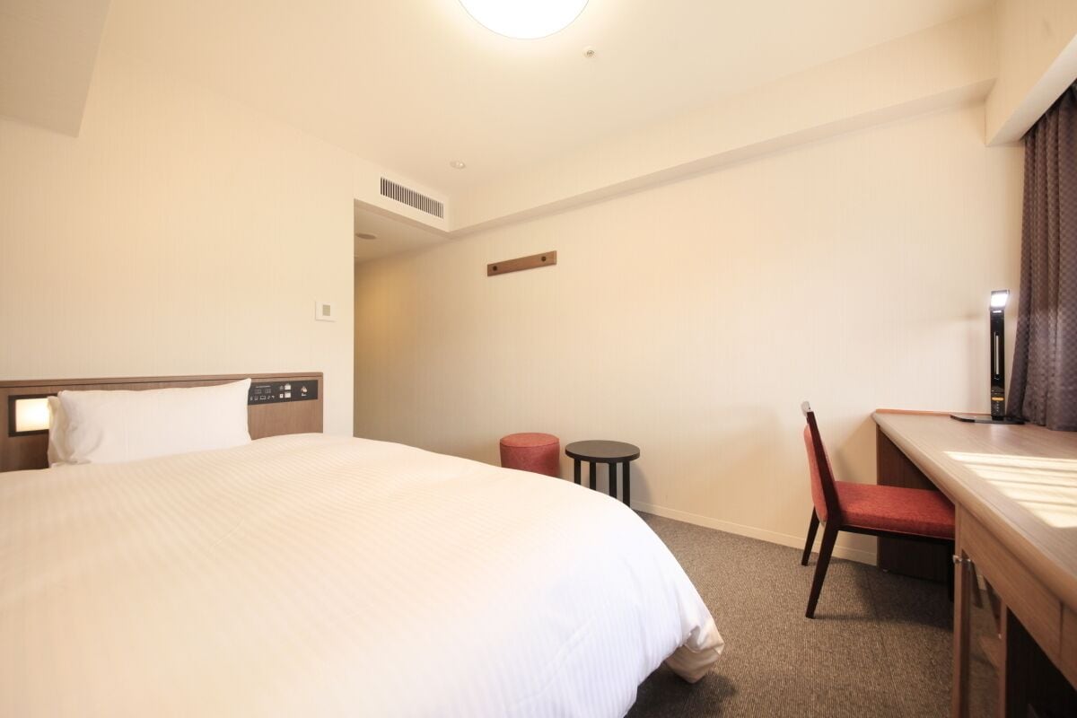 Une chambre d’hôtel avec un grand lit, un bureau avec une chaise et une petite table.
