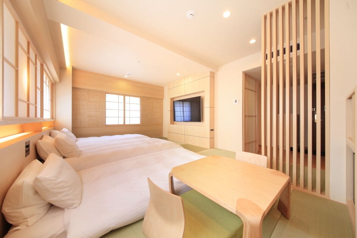 Habitación de hotel con cama, televisor, escritorio y puerta corredera.