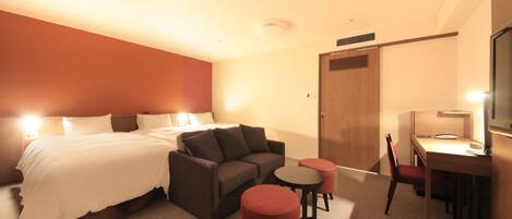 A hotel room with a bed, a sofa, a desk, a chair, and a small table.