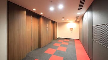 A hallway with wooden lockers, a red carpet, and a checkered wall panel.