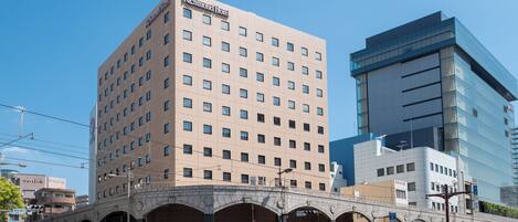 Hotel com fachada moderna, vários andares e entrada destacada com design em arco.