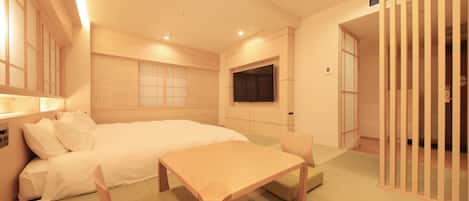 A hotel room with a bed, a TV, a desk, and a seating area.