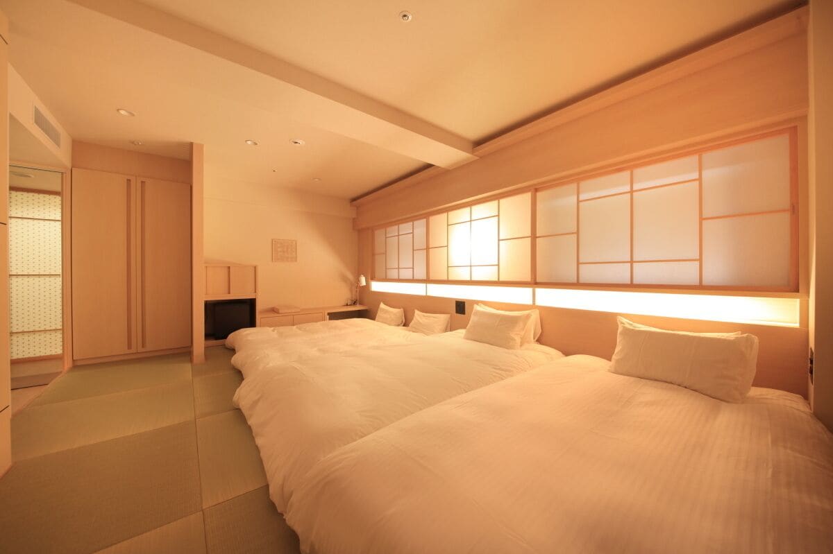 A hotel room with a large bed, a desk, and a traditional sliding door.