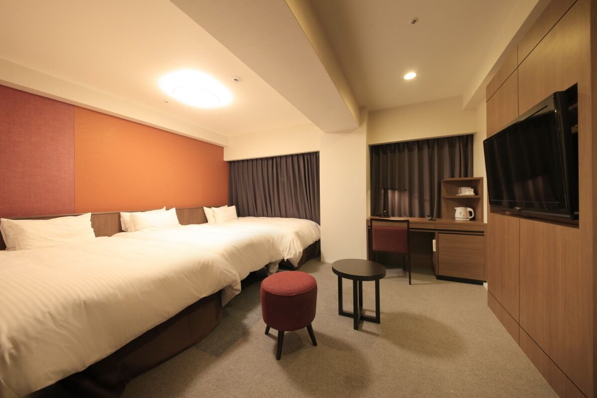 Habitación de hotel con una cama grande, una mesita redonda pequeña, un escritorio y un televisor.