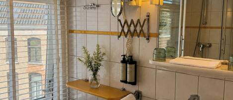 A bathroom with a sink, mirror, towel rack, and window with blinds.