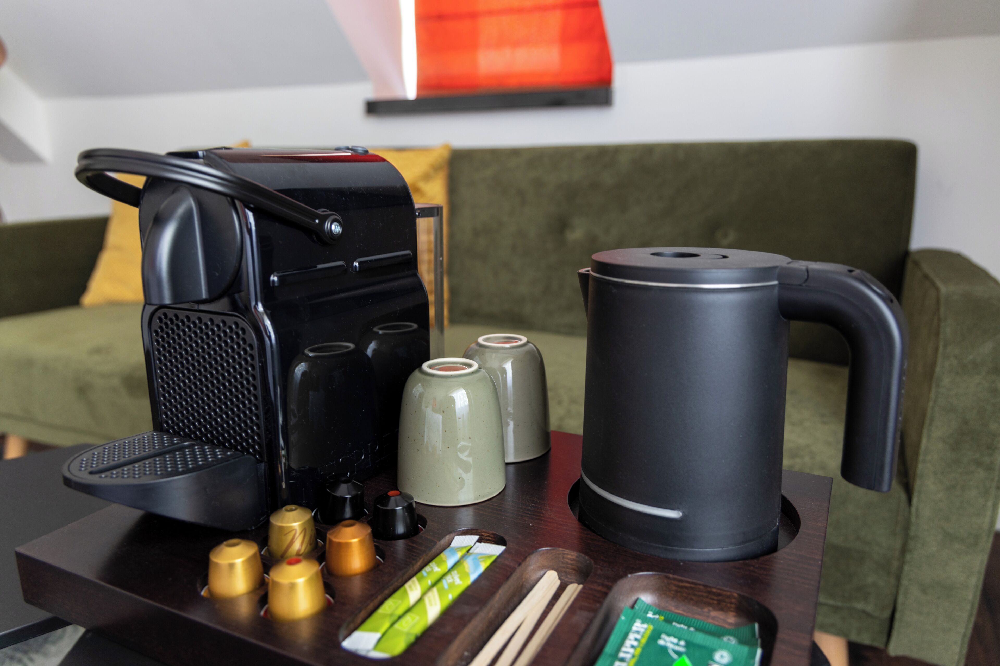 Una cafetera, un hervidor y un juego de recipientes para condimentos sobre una mesa.