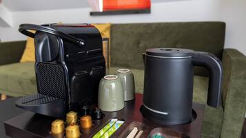 Una cafetera, un hervidor y un juego de recipientes para condimentos sobre una mesa.