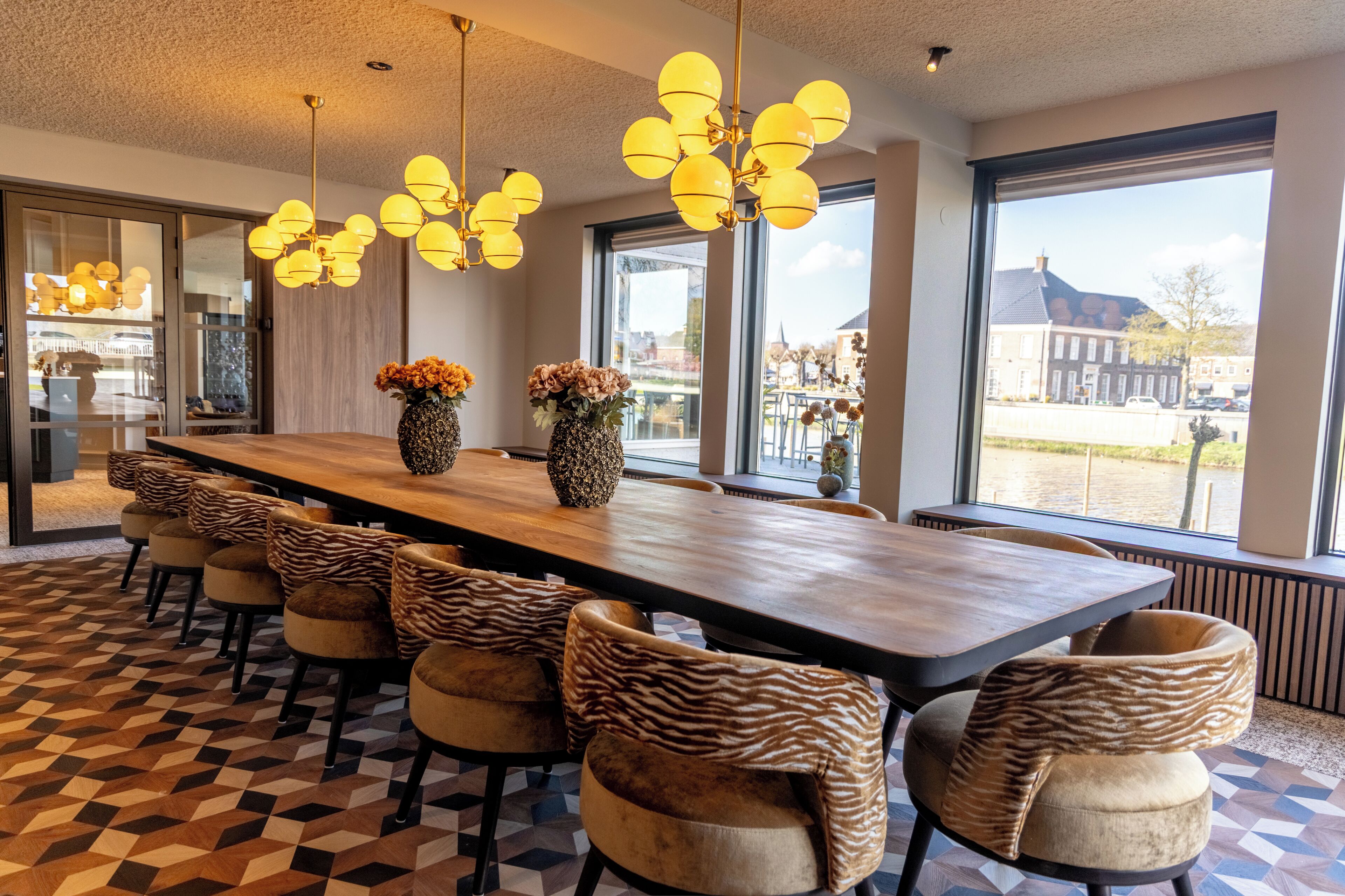 Un comedor moderno con una mesa larga, sillas estampadas de cebra y grandes ventanales con vistas.