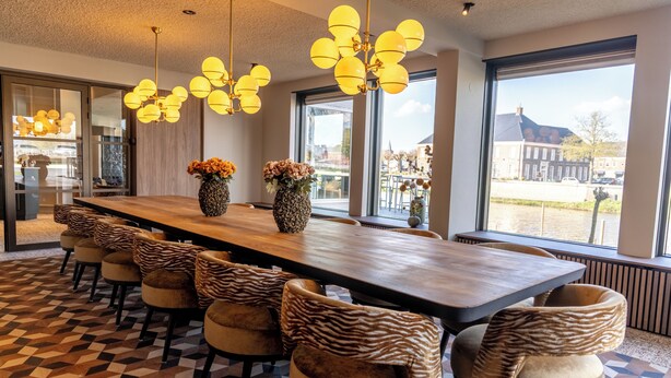 Un comedor moderno con una mesa larga, sillas estampadas de cebra y grandes ventanales con vistas.
