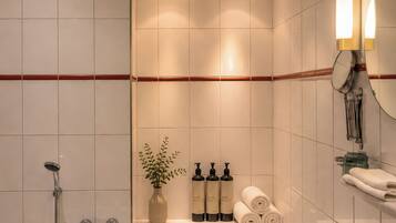 A modern bathroom with a bathtub, a sink, and a mirror. There is a shelf with toiletries and towels.