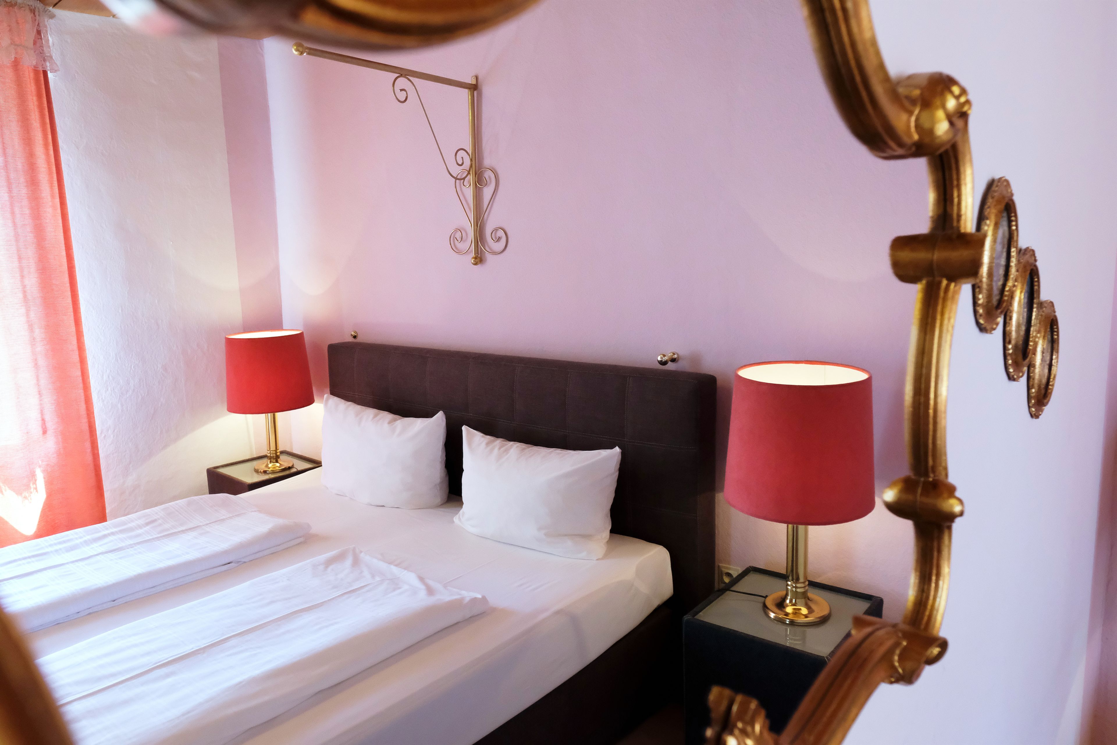 A neatly made bed with white linens, two bedside lamps, and a decorative wall hanging.