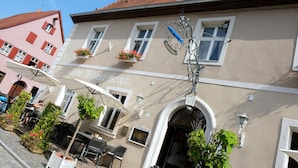 A building with a sign reading "Hotel Bayerischer Hof" and outdoor seating with umbrellas.