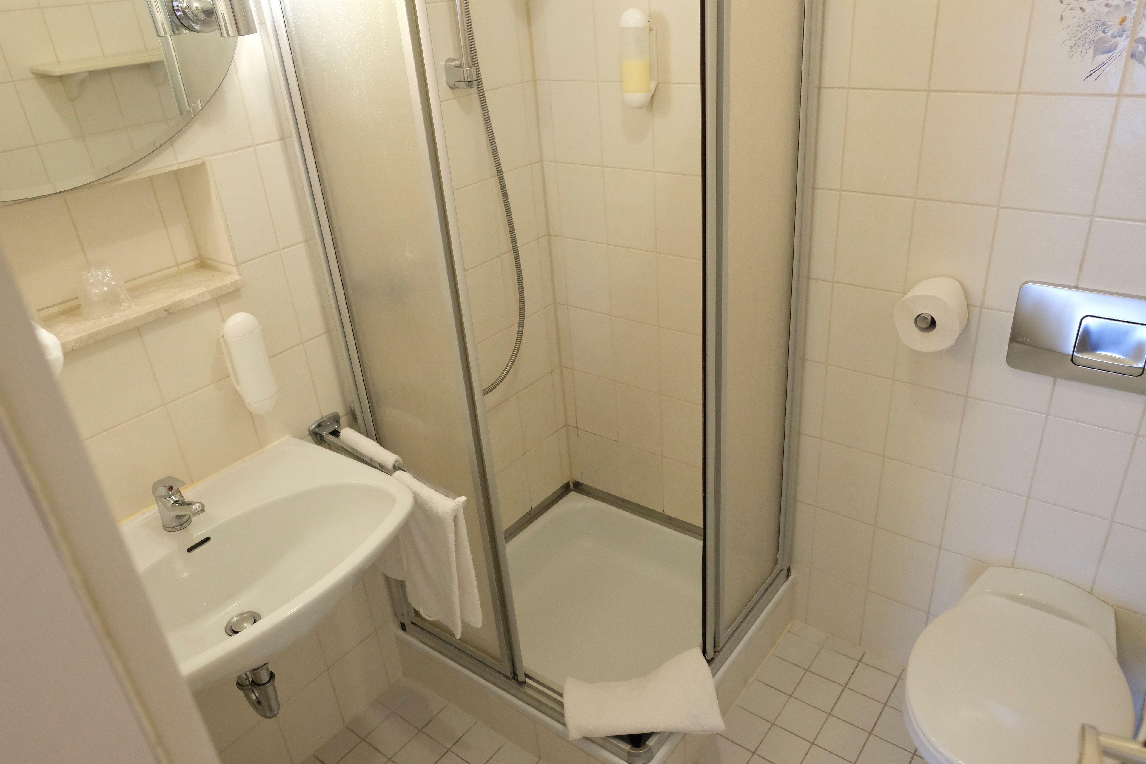 A bathroom with a sink, toilet, and glass-enclosed shower.