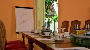 A conference room with a whiteboard displaying 'Willkommen' and a table set with cups, saucers, and a bottle.