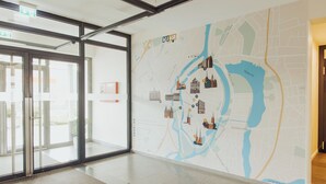 Un vestíbulo de hotel con un gran mapa mural, puertas de vidrio y piso alfombrado.