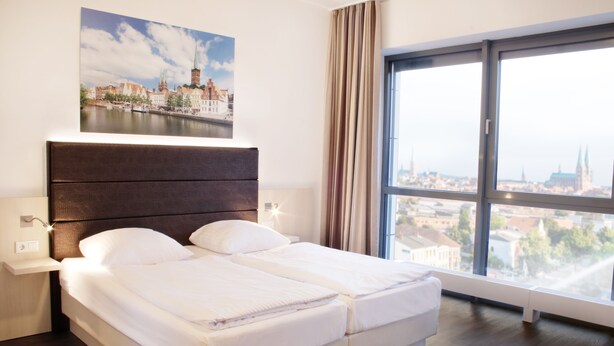 Una habitación de hotel moderna con una cama grande, vista a la ciudad y un cuadro de un puente.