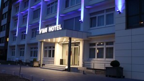 Un hotel moderno con una entrada destacada y señalización iluminada.