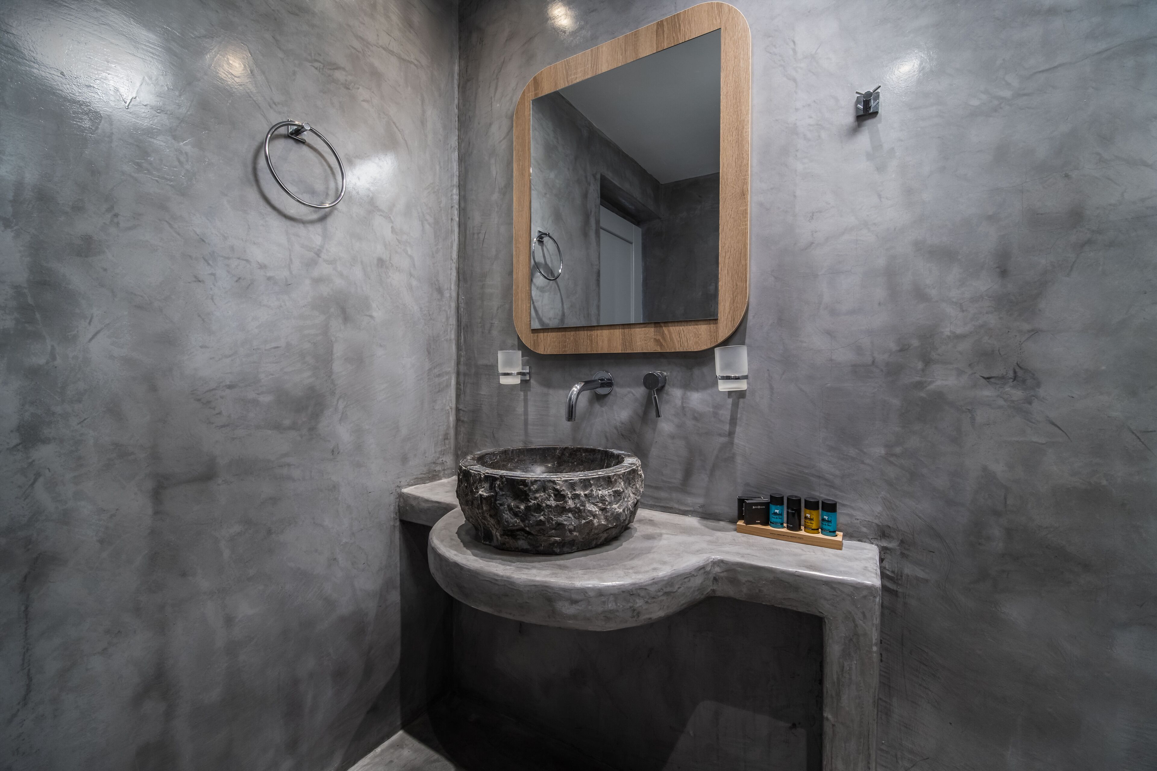 A bathroom with a stone sink, a wooden-framed mirror, and a towel ring.