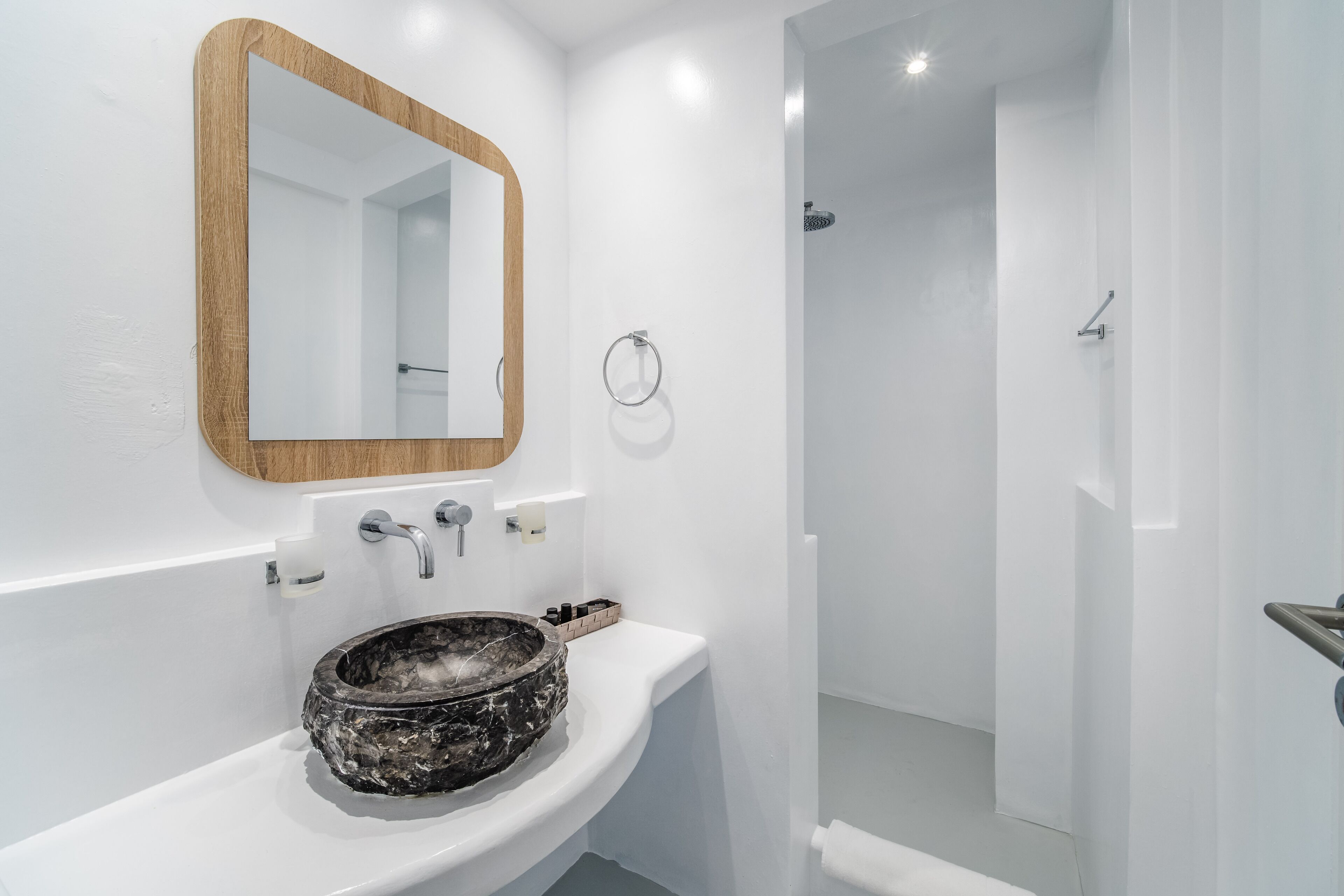 A bathroom with a white sink, a wooden-framed mirror, and a shower area.