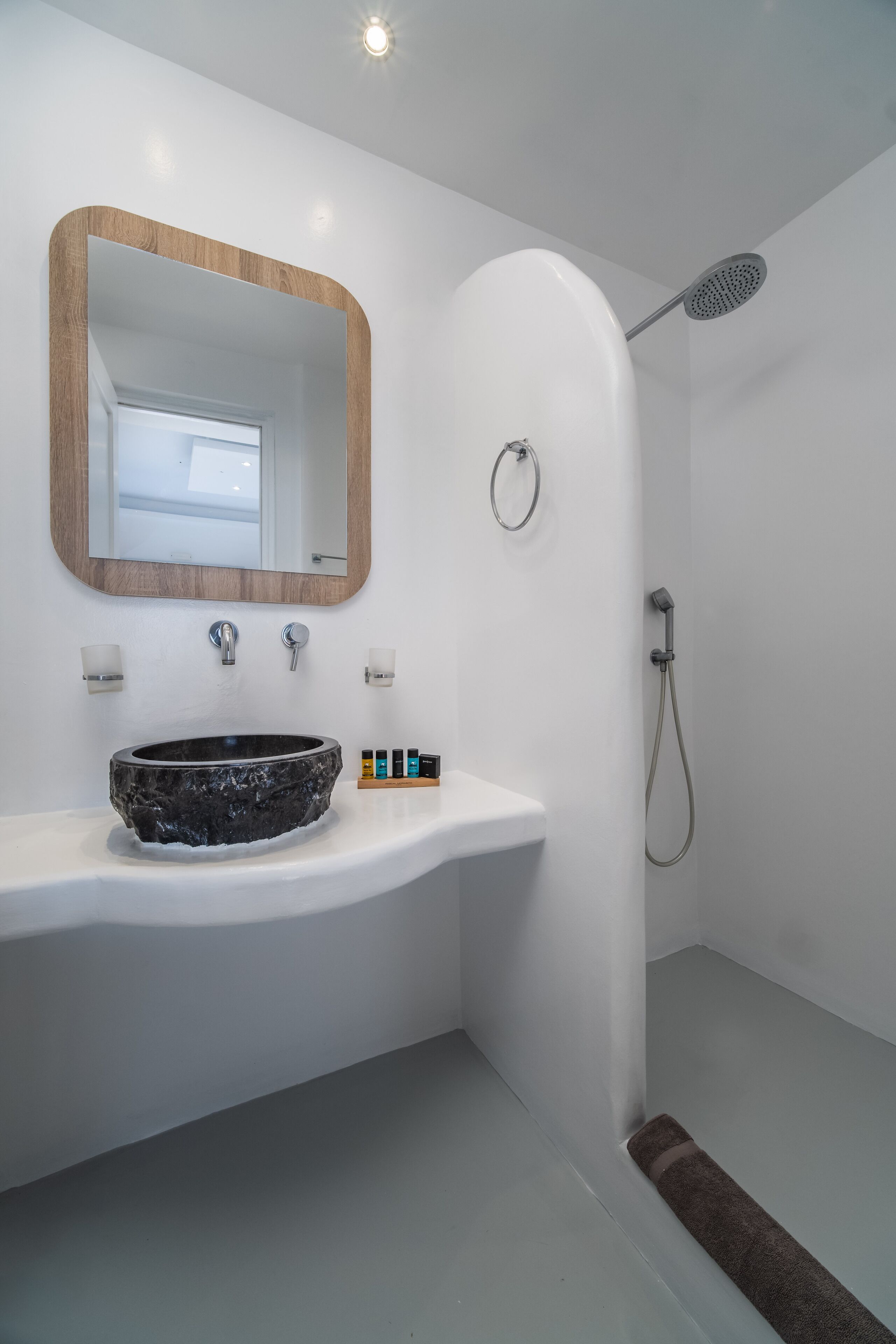 A modern bathroom with a large oval sink, a wooden-framed mirror, and a shower area.