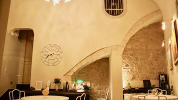 A restaurant with stone walls, a clock, and tables with chairs.