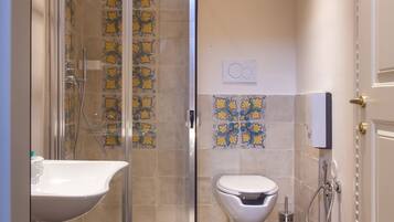 Un baño con cabina de ducha de vidrio, un lavabo blanco, un inodoro y azulejos decorativos.