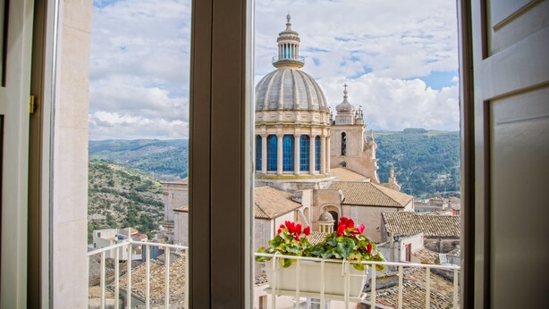 Vista di un edificio storico con una cupola e colonne, ripresa da un balcone con ringhiera.