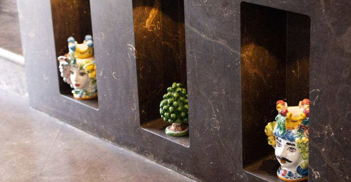 A row of dark-colored cabinets with small windows, each containing a different decorative item.