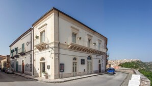 Un edificio storico con uno stile architettonico classico, caratterizzato da un ingresso centrale, balconi e una vista panoramica sui dintorni.