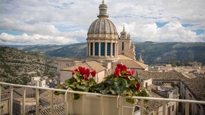 Una veduta di un edificio storico con una cupola e un campanile, immerso in un paesaggio collinare.