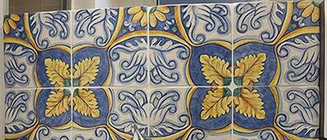 Une salle de bain avec un lavabo blanc, un miroir et des carreaux décoratifs ornés de motifs floraux.